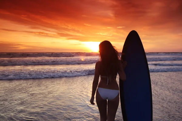 Surfer kobieta na plaży o zachodzie słońca — Zdjęcie stockowe
