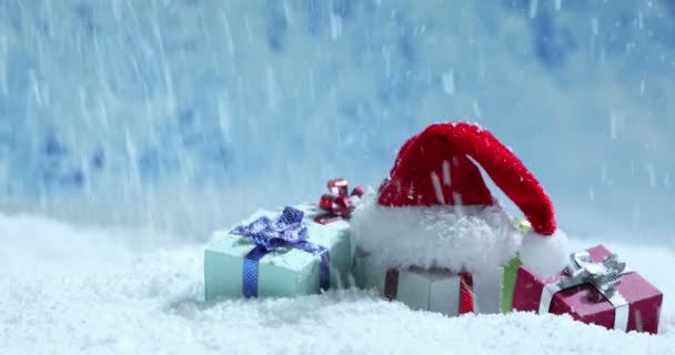 Weihnachtsmütze Und Kleine Dekorative Geschenke Unter Fallendem Schnee Weihnachten Neujahr — Stockvideo