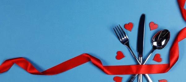 青い背景に赤いシルクリボンと心で結ばれたかわいいセットバレンタインデーのディナーコンセプト — ストック写真