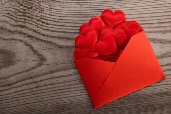 バレンタインデーの愛の手紙 木製の背景に赤いハートヒープを持つクラフト赤い紙の封筒 — ストック写真