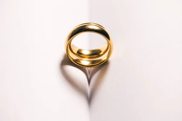 两个金婚戒指在空白的书页背景上 有抄袭的文字空间 心形影子爱情的概念 — 图库照片