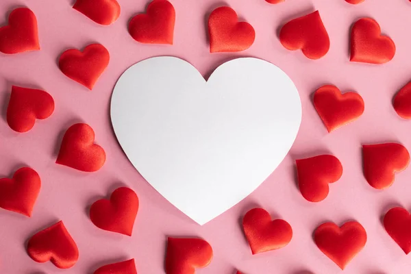 バレンタインデーコピースペース 愛の概念とピンクの背景に多くの赤い絹の心と白いハート型のカード — ストック写真