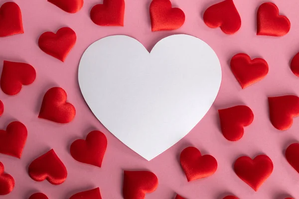 バレンタインデーピンクの背景に多くの赤い絹の心と白いハート型のカード 愛の概念 — ストック写真