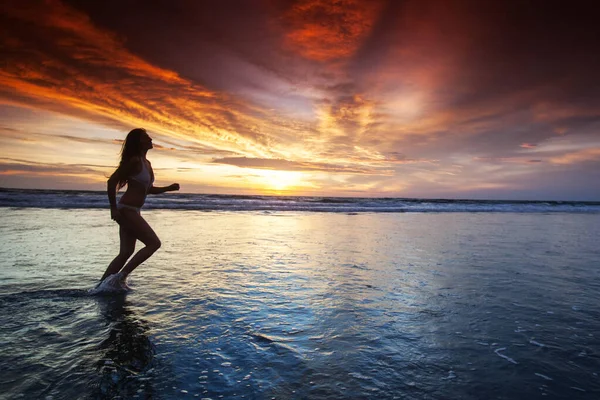 日落时在海滩边奔跑的女人 — 图库照片