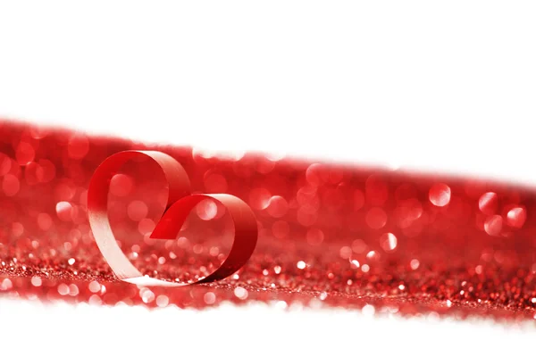 Red ribbon heart on glitters — Stock Photo, Image