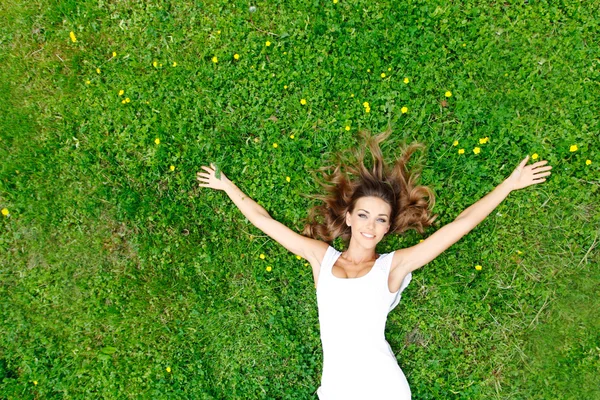 Jonge vrouw in witte jurk liggen op gras — Stockfoto