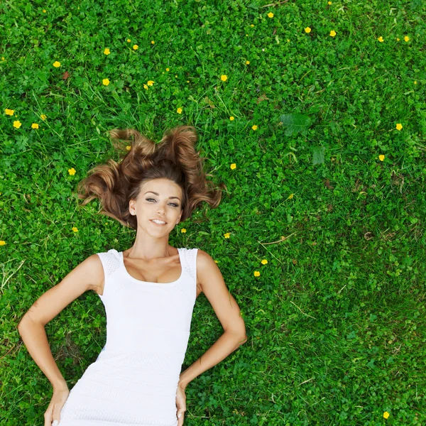 Jonge vrouw in witte jurk liggen op gras — Stockfoto