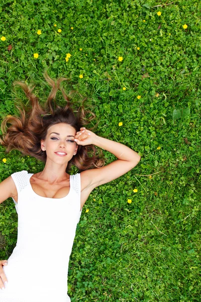 Giovane donna in abito bianco sdraiata sull'erba — Foto Stock