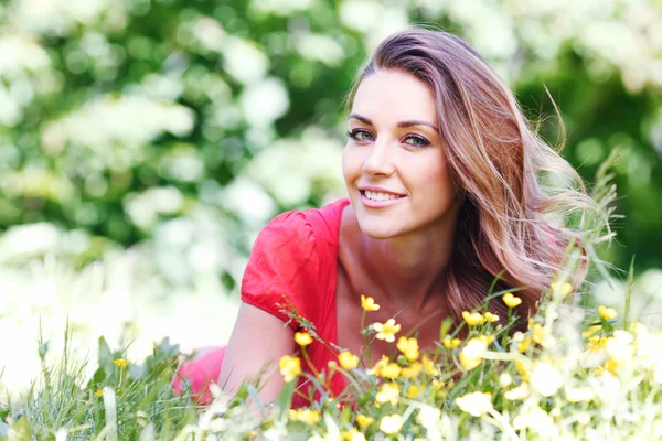 Jeune femme en robe rouge couchée sur l'herbe — Photo