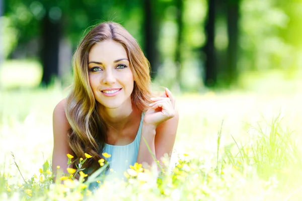 Young woman in blue dress lying on grass — Stock Photo, Image