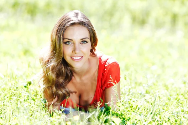 Junge Frau in rotem Kleid auf Gras liegend — Stockfoto