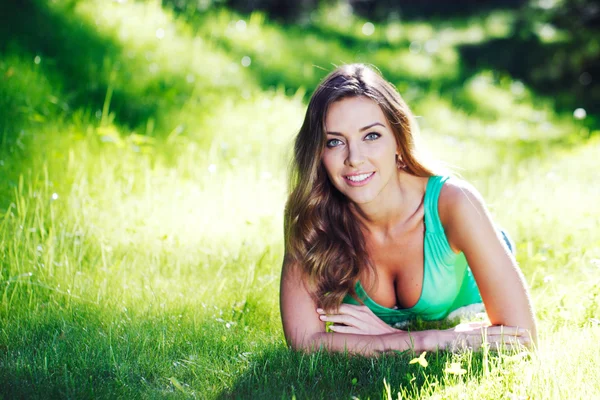 Çim üzerinde yalan yeşil giysili genç kadına — Stok fotoğraf
