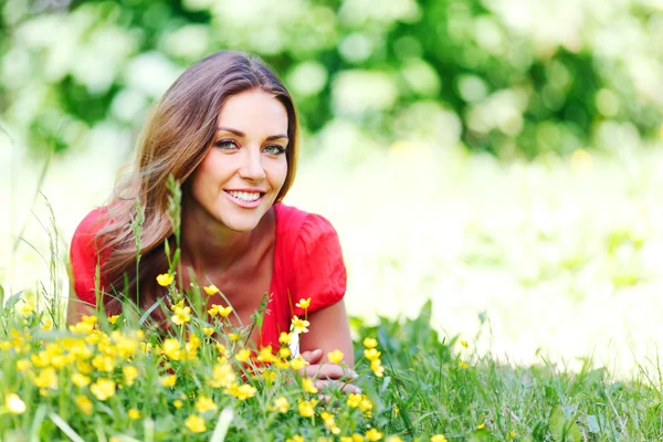 Jonge vrouw in rode jurk liggend op gras — Stockfoto