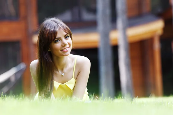 Jonge vrouw in gele jurk liggen op gras — Stockfoto