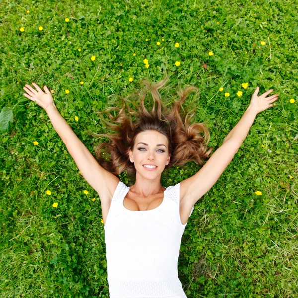 Young woman in white dress lying on grass — Stock Photo, Image