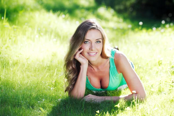 Jonge vrouw in groene jurk liggen op gras — Stockfoto