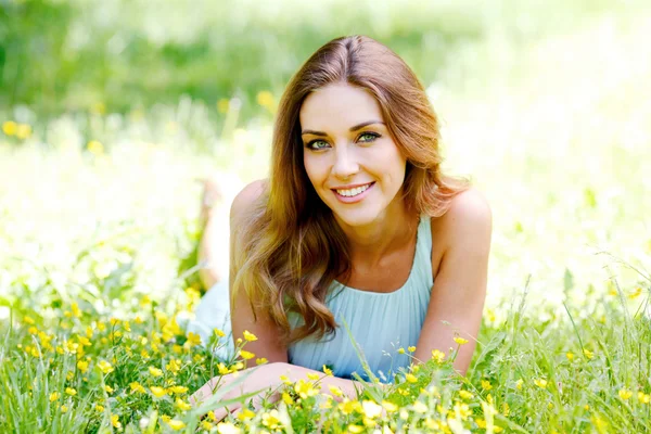 Jonge vrouw in blauwe jurk liggen op gras — Stockfoto