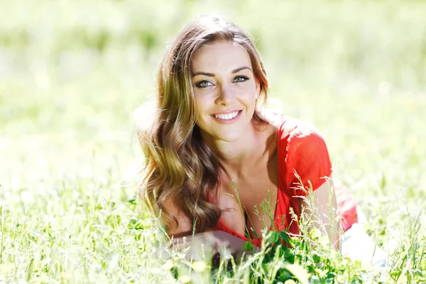 Junge Frau in rotem Kleid auf Gras liegend — Stockfoto