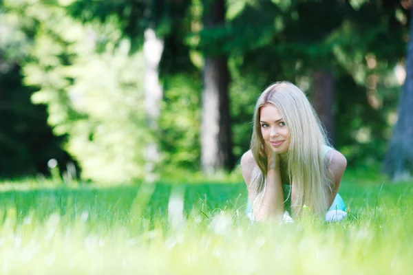 Jonge vrouw in blauwe jurk liggen op gras — Stockfoto