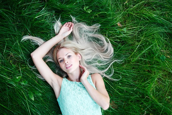 Junge Frau in blauem Kleid auf Gras liegend — Stockfoto