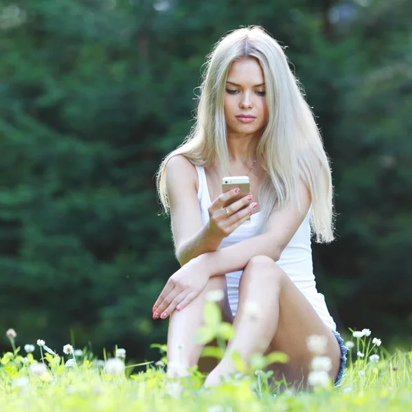 Ung blond kvinna sitter på gräset — Stockfoto