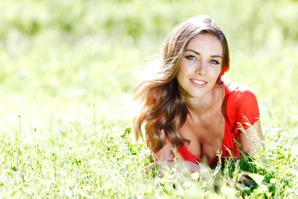 Junge Frau in rotem Kleid auf Gras liegend — Stockfoto
