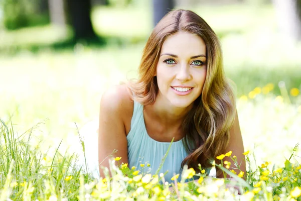 Young woman in blue dress lying on grass — Stock Photo, Image