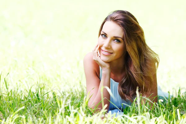 Jeune femme en robe bleue couchée sur l'herbe — Photo