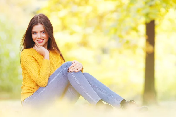 Brunette vrouw zitten in de herfst park — Stockfoto