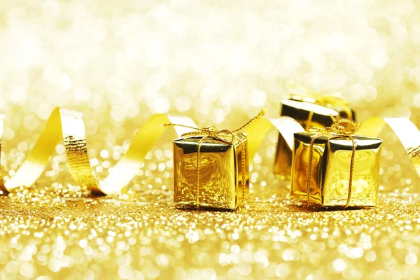 Small decorative golden presents on glitter background — Stock Photo, Image