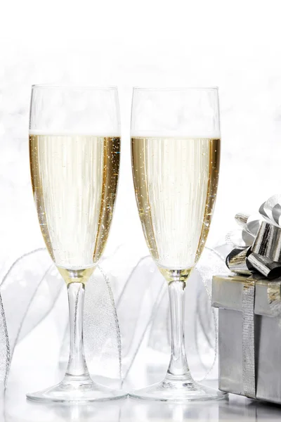 Gläser Champagner und silberne Geschenke auf Glitzerhintergrund — Stockfoto