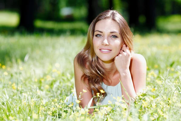 Jeune femme en robe bleue couchée sur l'herbe — Photo