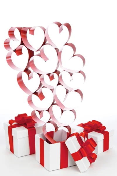 Kırmızı kurdeleli beyaz kutular ve beyaz arka planda izole dekoratif kalpler. — Stok fotoğraf