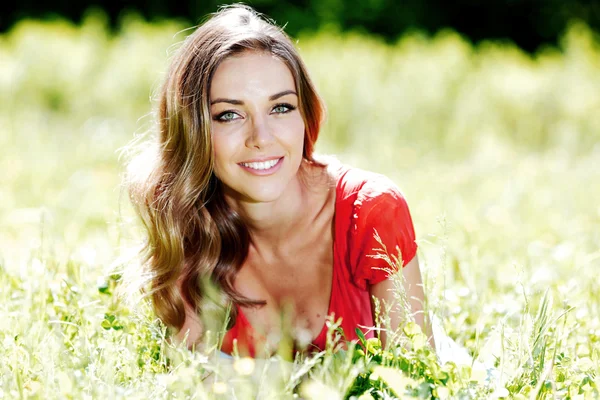 Young woman in red dress lying on grass — Stock Photo, Image