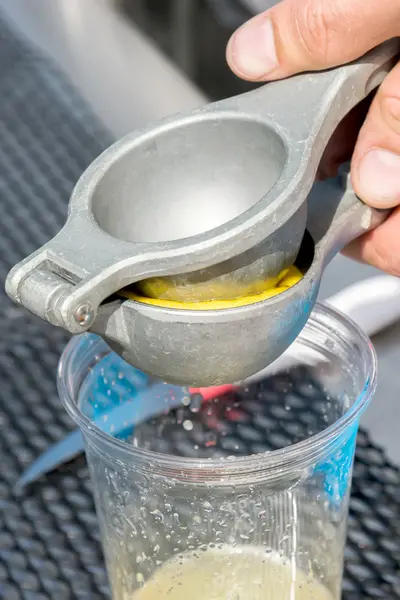 Exprimidor manual de metal limón en una taza de plástico —  Fotos de Stock