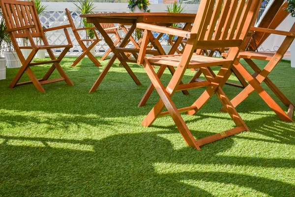 Ahşap sandalye ve masa yeşil çimenlerin üzerinde — Stok fotoğraf