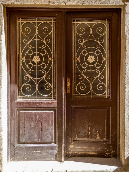 Vieja puerta de madera andrajosa con barras de hierro forjado — Foto de Stock