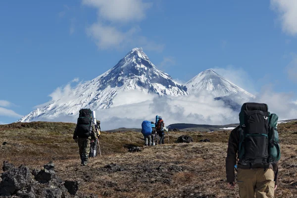 Hikers group trekking in mountain on background of volcanos