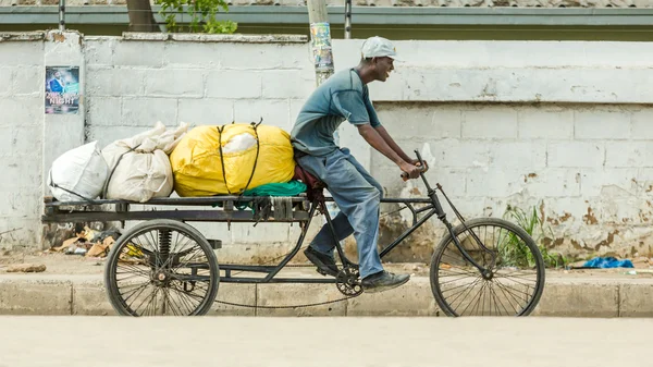 Homem montando sua bicicleta personalizada equipada com um reboque carregado — Fotografia de Stock