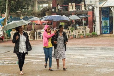 Üç kadın Addis sokaklarında yürürken bir şemsiye ile 