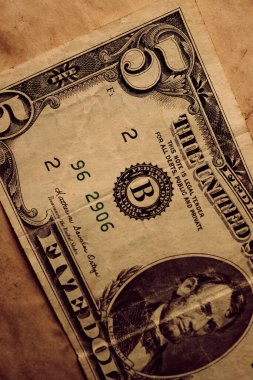 Yoksulluk kavramı arka planında bej rengi, hasarlı kağıt yüzey üzerine beş dolarlık bir banknot.