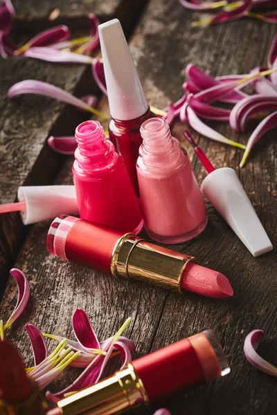 Lipsticks, nail polish and flower petals — Stock Photo, Image