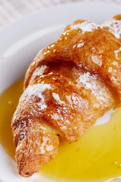 Croissant with honey — Stock Photo, Image