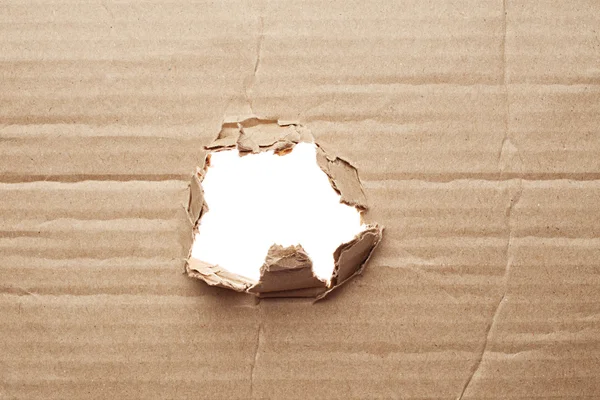 Torn hole in cardboard — Stock Photo, Image