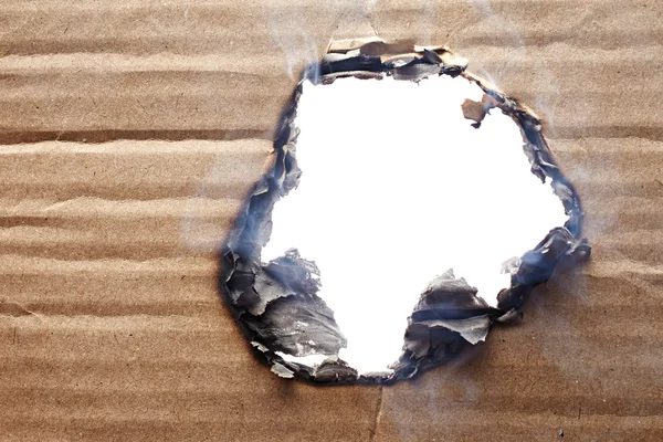 Burnt hole in cardboard — Stock Photo, Image