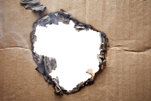 Burnt hole in cardboard — Stock Photo, Image