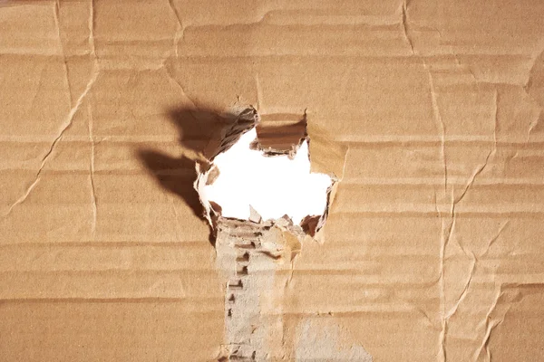 Torn hole in cardboard — Stock Photo, Image