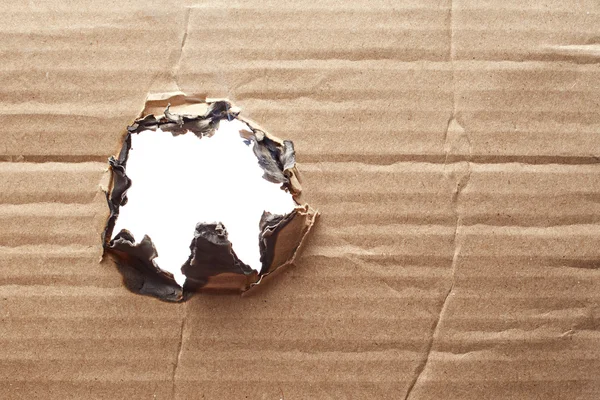 Burnt hole in cardboard — Stock Photo, Image