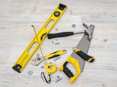 Ahşap DIY tezgah üzerinde üstten görünüm İnşaat aletleri ve araçları. Seviye, gördüm, gözlük, mezura, İngiliz anahtarı, anahtar, boya rulo, çekiç, kesici, pense.