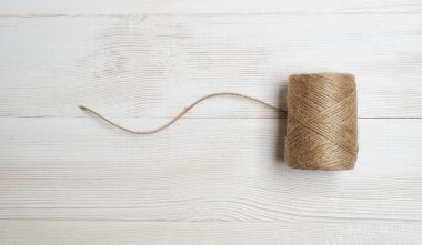 Spool of wool thread on a white wooden background. Top view desktop